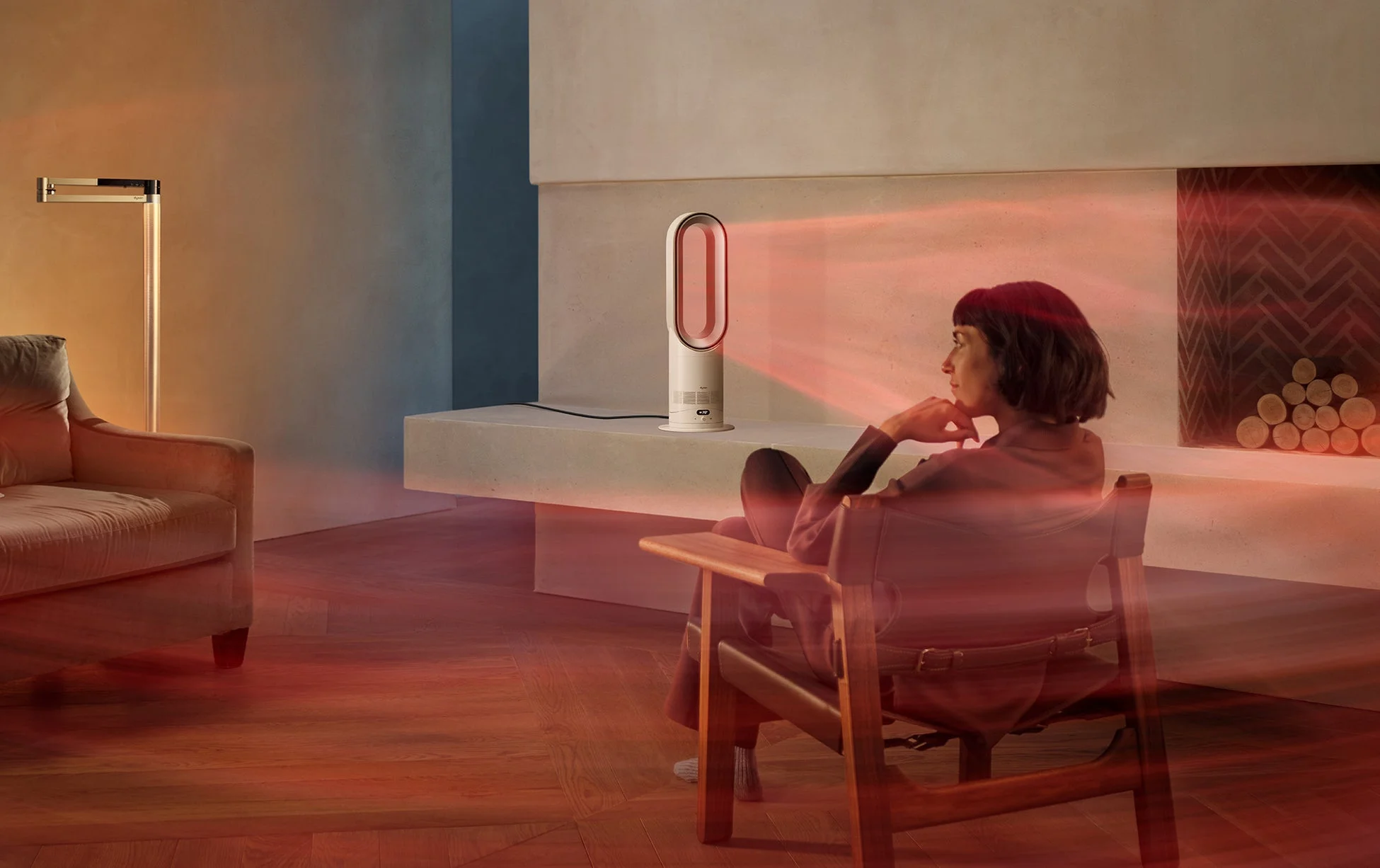 現代的なリビングルームで、女性がダイソンのファンヒーターの温かい光を浴びながらリラックスしている様子。