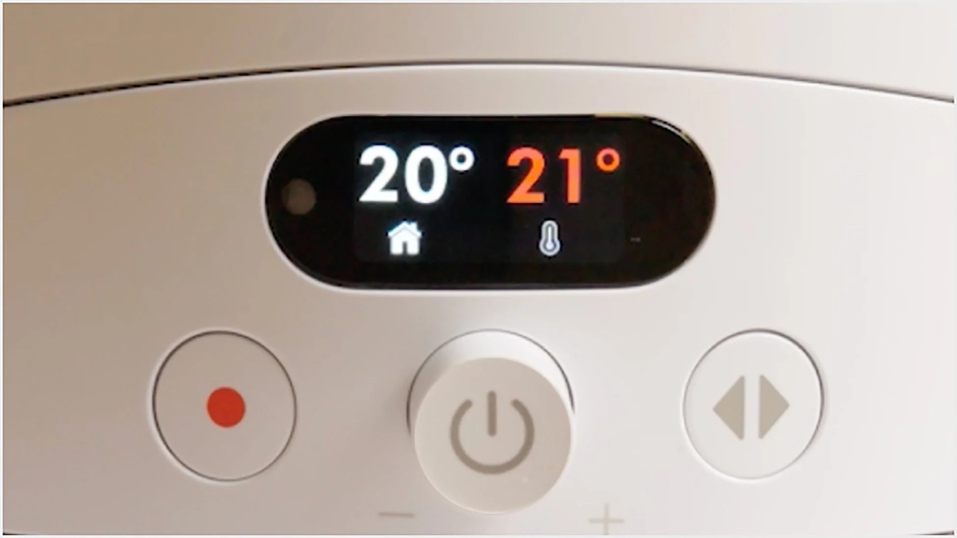 白いスマートホーム機器の操作パネルのクローズアップ。デジタルディスプレイには室温20°と設定温度21°が表示されており、電源ボタンや設定調整用のボタンが見える。