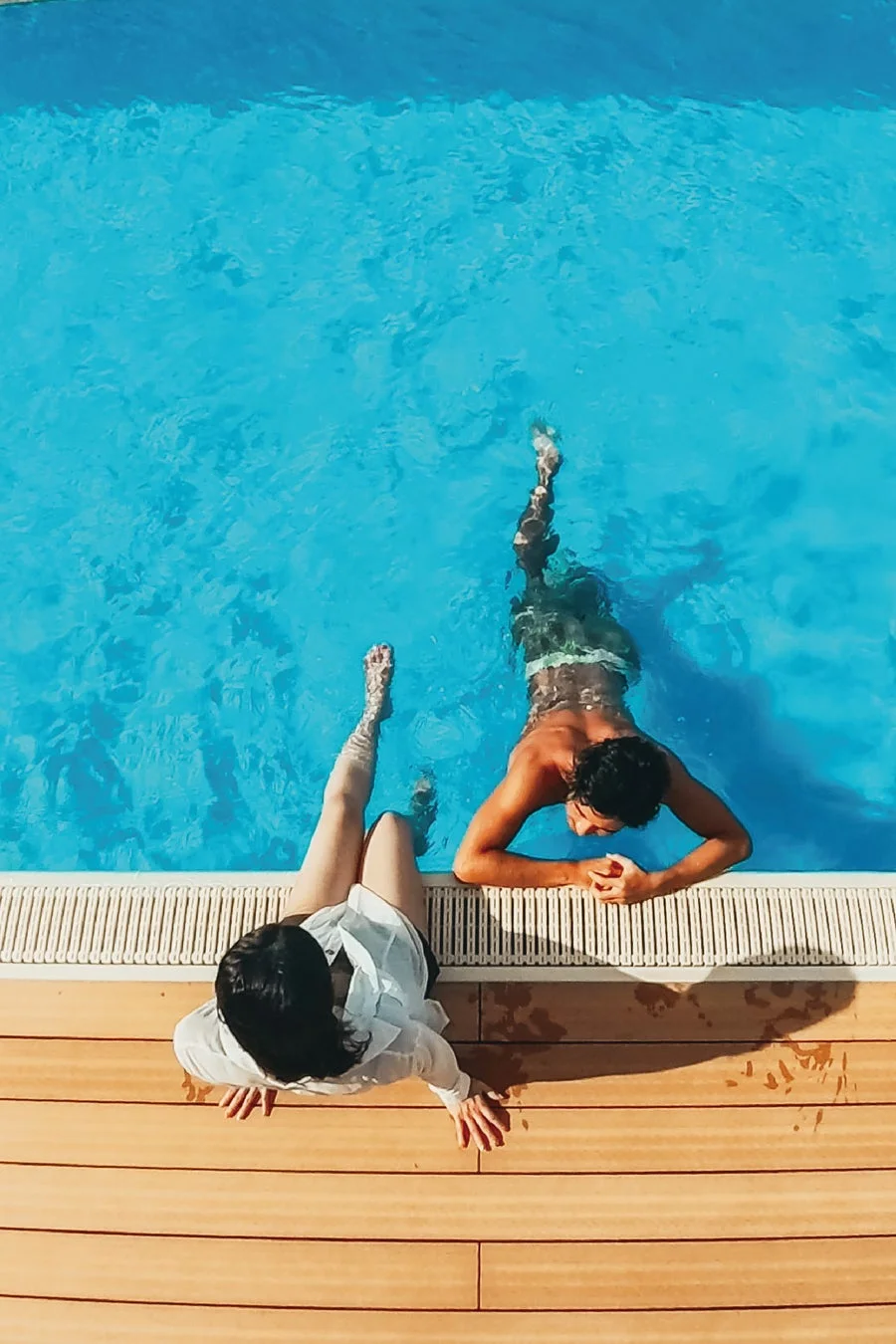 プールサイドでリラックスする男女