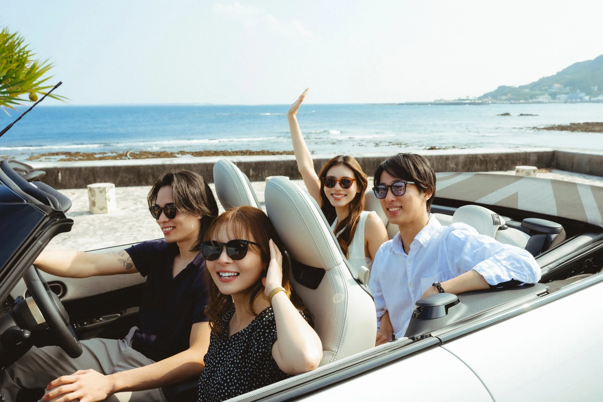 海沿いをコンバーチブルでドライブを楽しむ若者たち