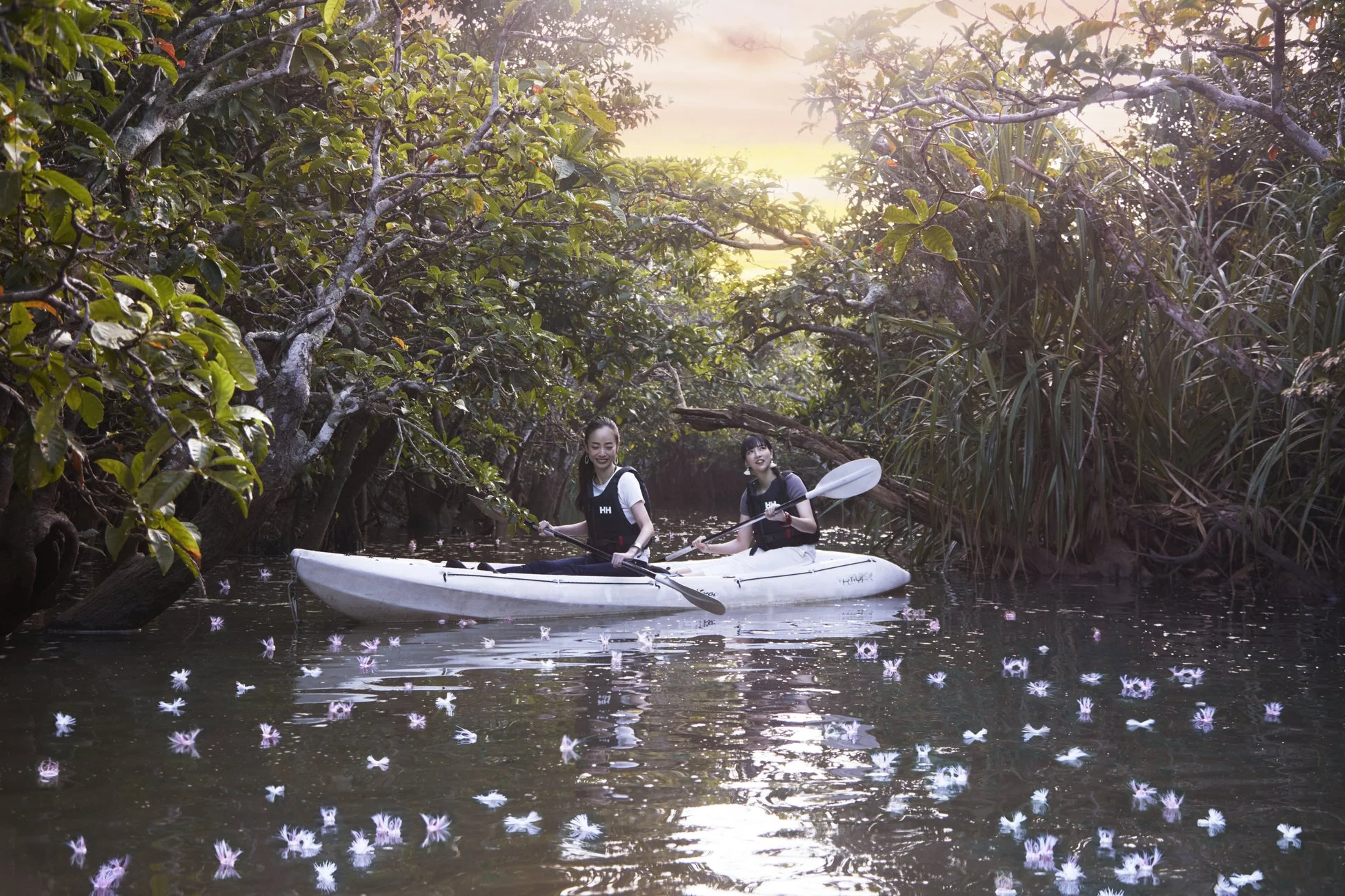 カヤックで水面に浮かぶ花を楽しむ女性たち