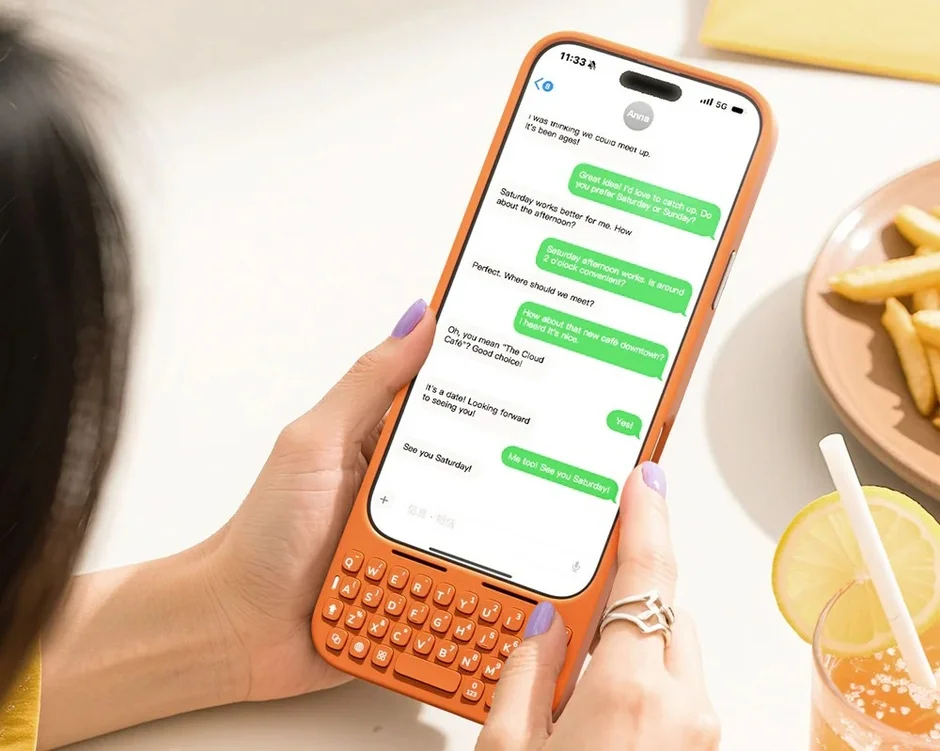 オレンジ色の物理キーボード付きスマートフォンを操作する女性の手元