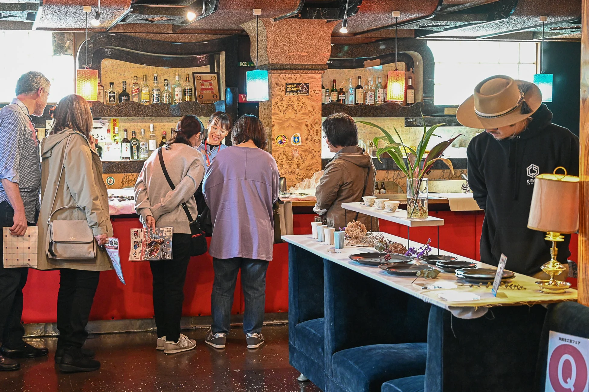 バーカウンターのある店内で人々が商品を見て交流