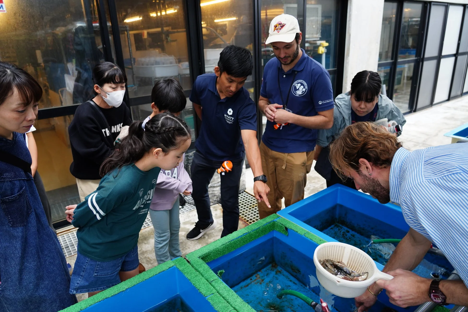 水槽を囲んで海洋生物を観察する子供たちと大人