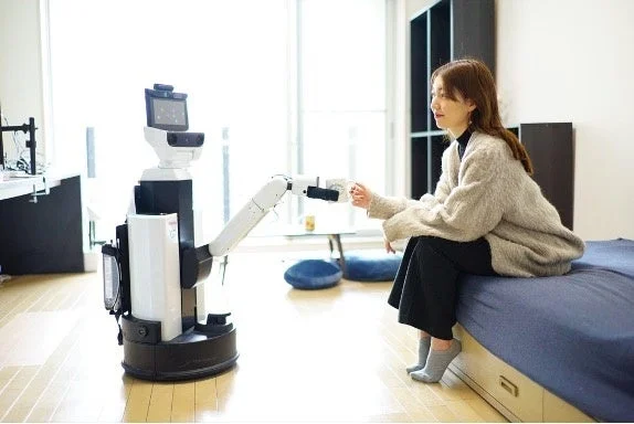 ロボットが女性にマグカップを渡す様子