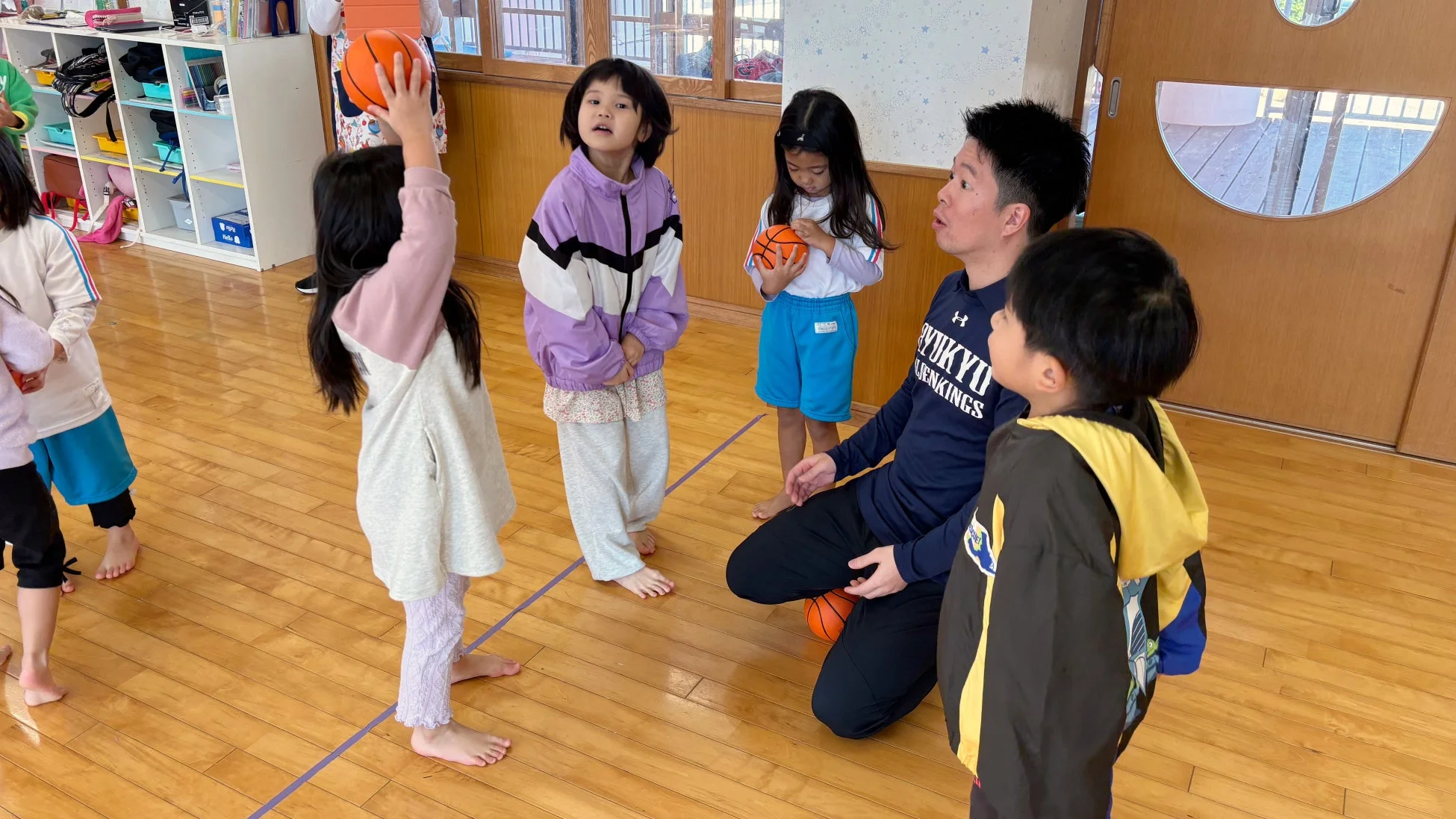 コーチからバスケットボールを学ぶ子どもたち
