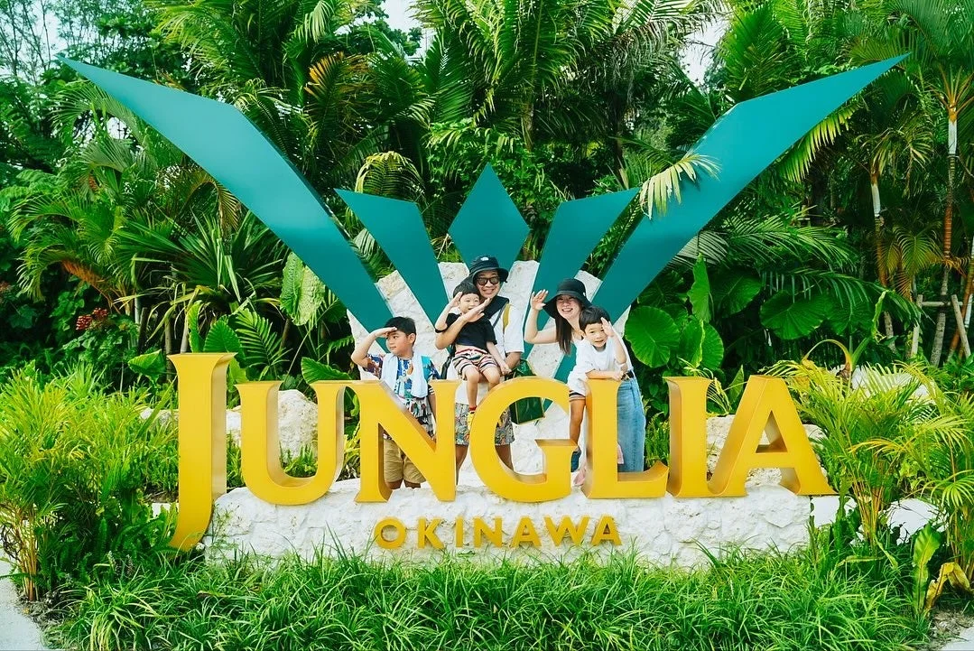 JUNGLIA OKINAWAのロゴ前で家族が記念撮影