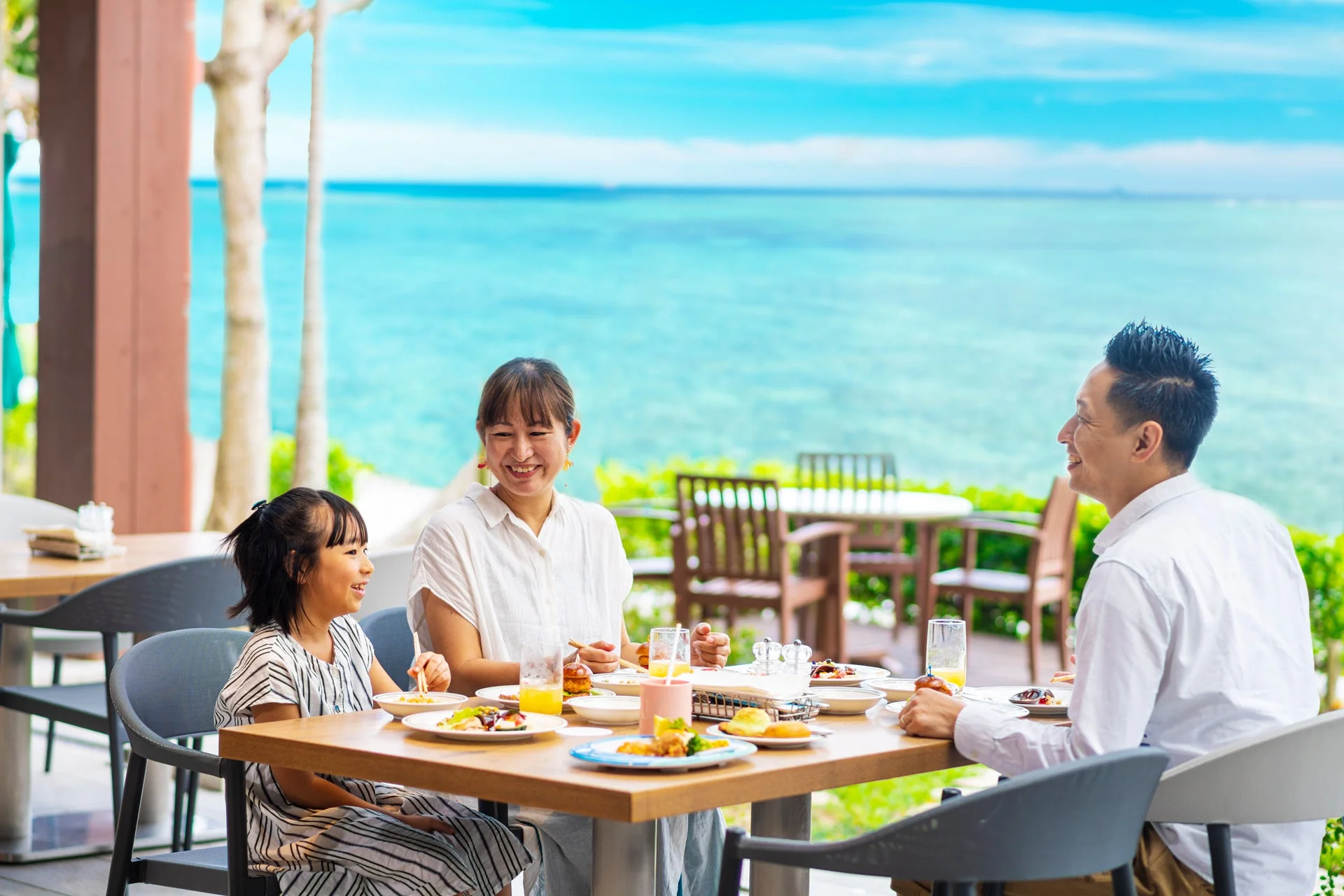 海を背景に食事を楽しむ家族
