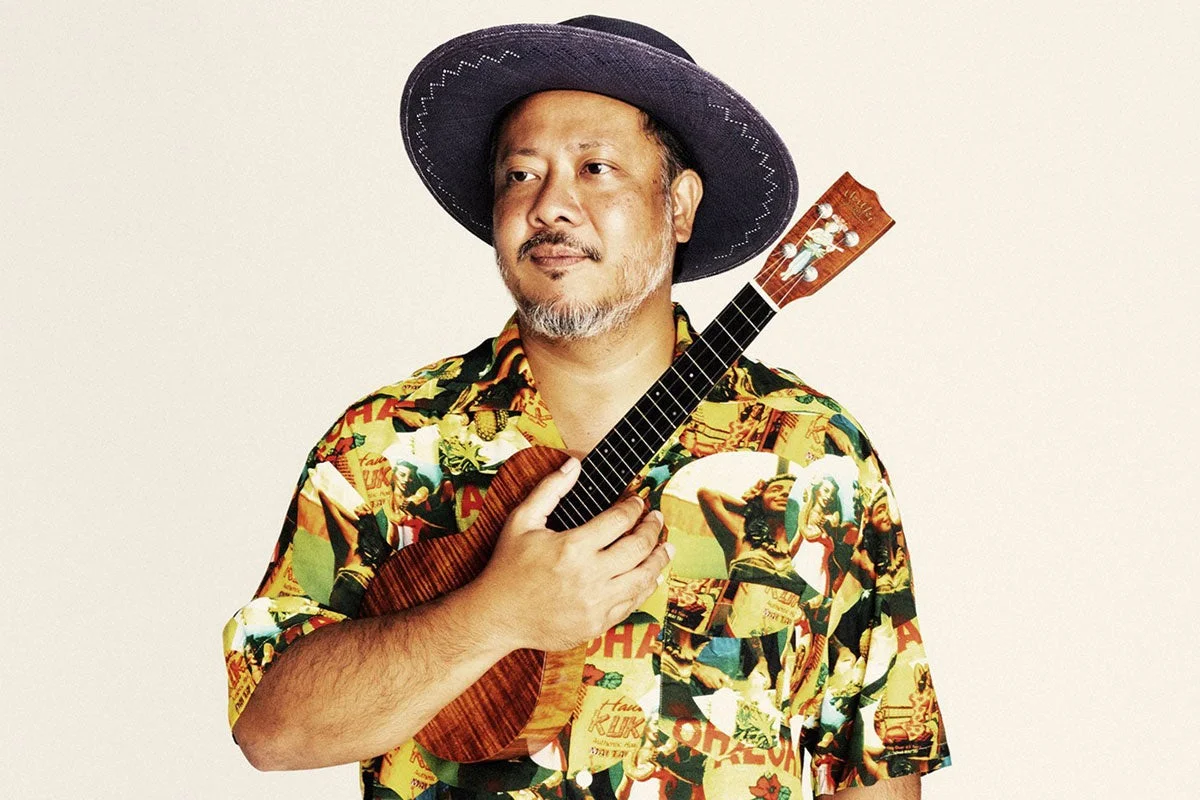 帽子をかぶり、アロハシャツを着た男性がウクレレを抱えているポートレート