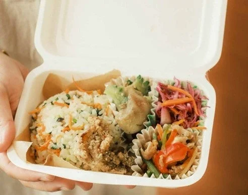 手に持った使い捨て容器入りの弁当