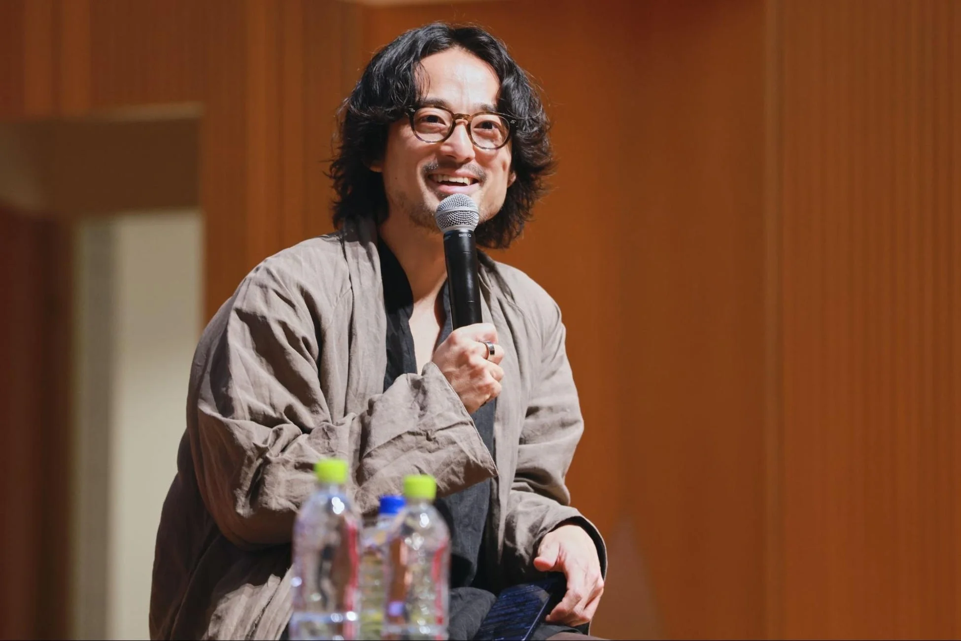 男性がマイクを手に笑顔で話している様子