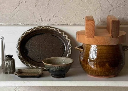 素朴な和食器と木製の蓋がついた大きな陶器の漬物器