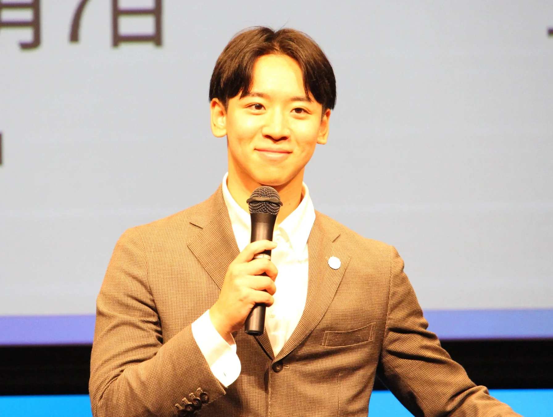 スーツ姿でマイクを持って話す中尾香達氏