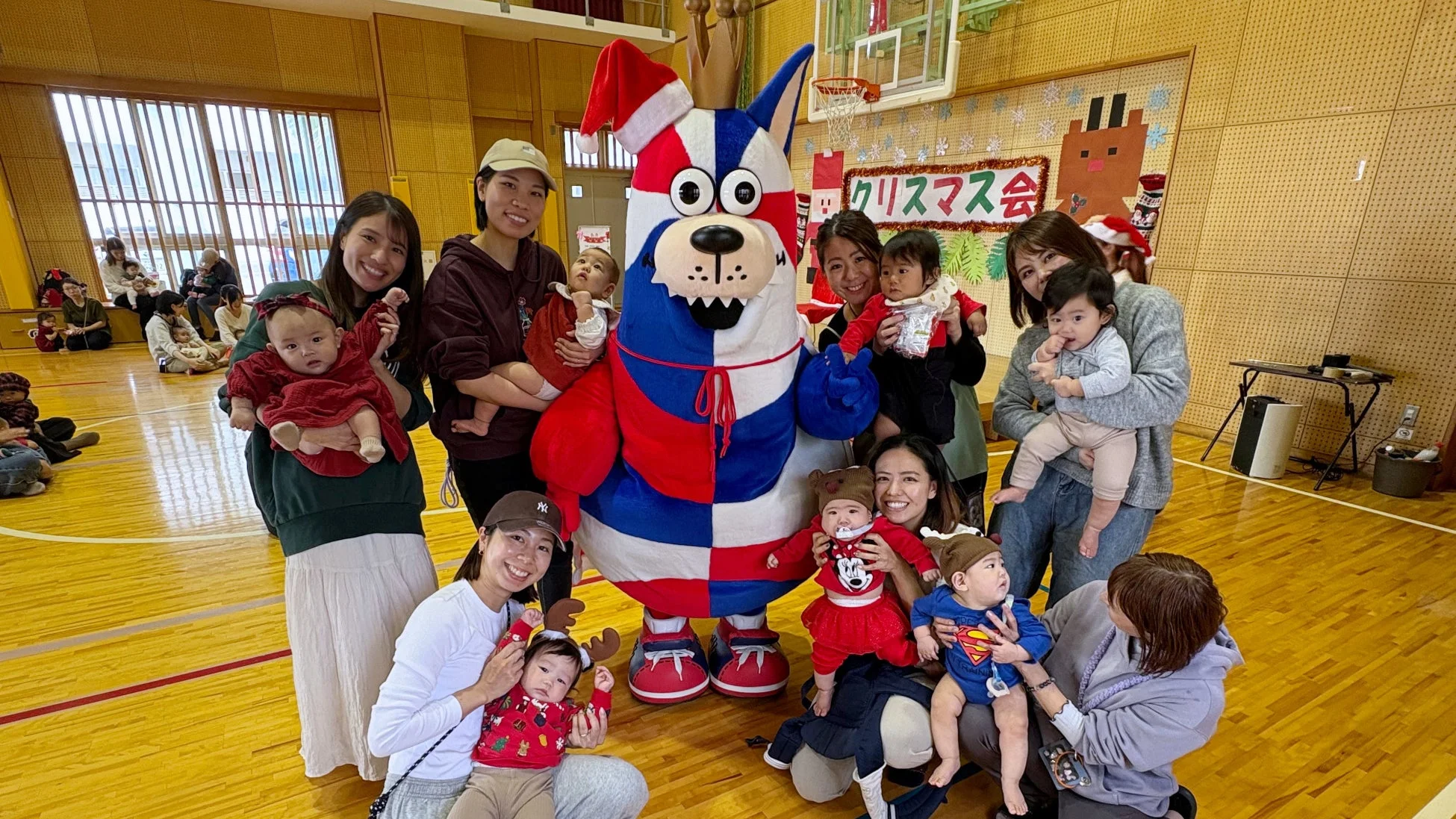 サンタ帽をかぶったゴーディーと記念撮影をする親子