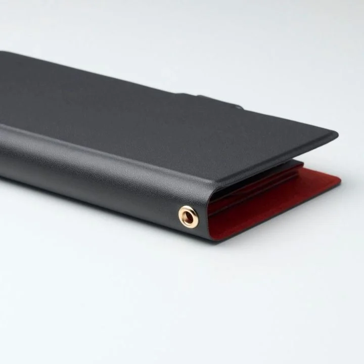 黒いバインダーまたはファイルフォルダが写っており、内側は鮮やかな赤色