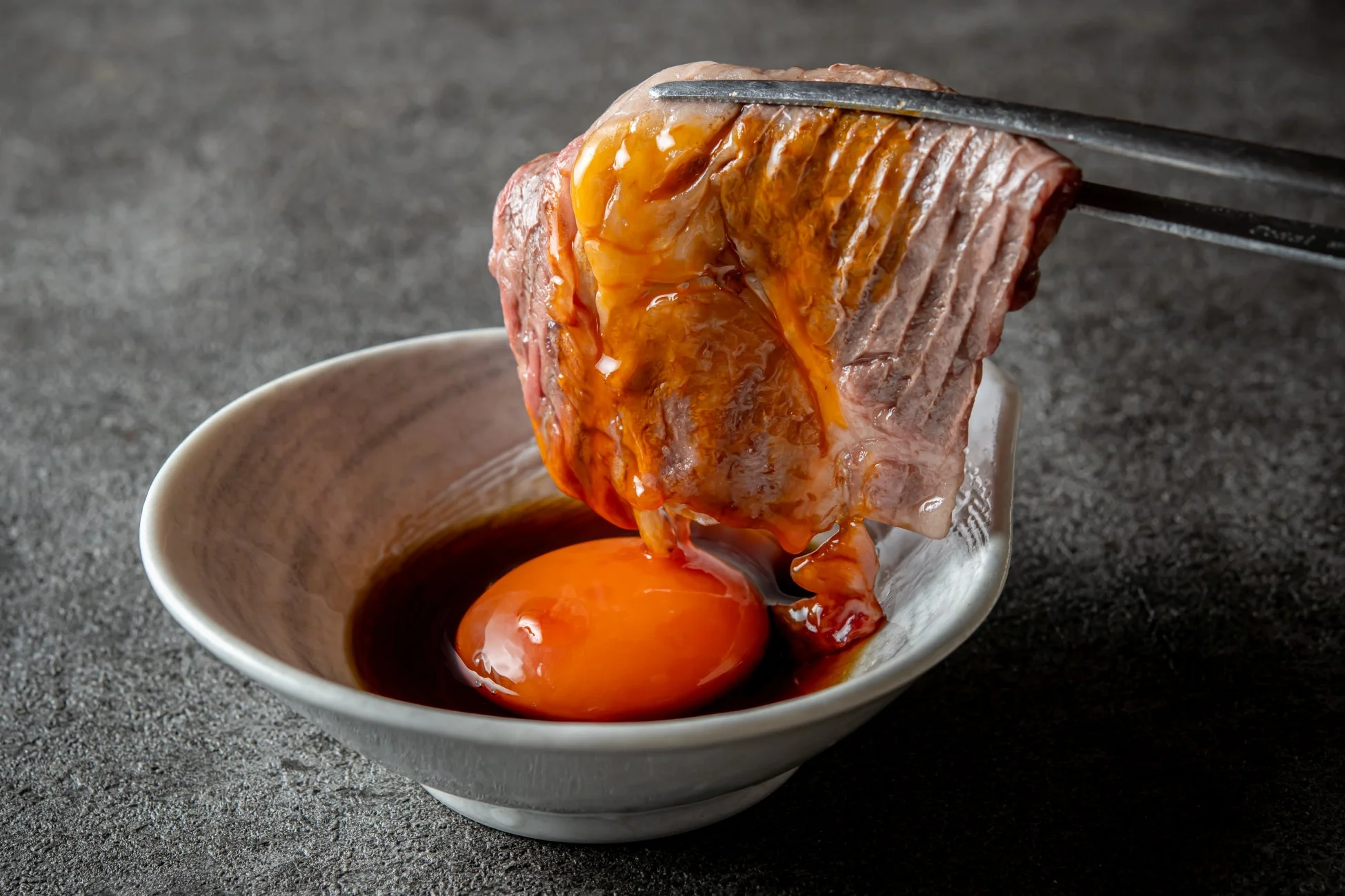 焼いた肉が生卵に浸されている様子