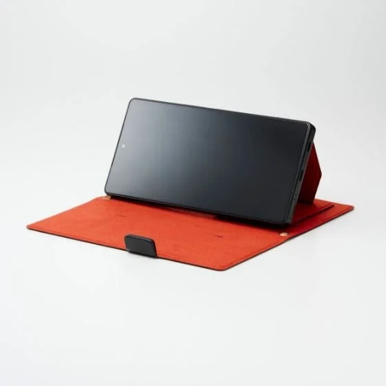 白い背景の上に、赤い折りたたみ式ケースをスタンドとして使い、横向きに立てられた黒いタブレットまたはスマートフォン