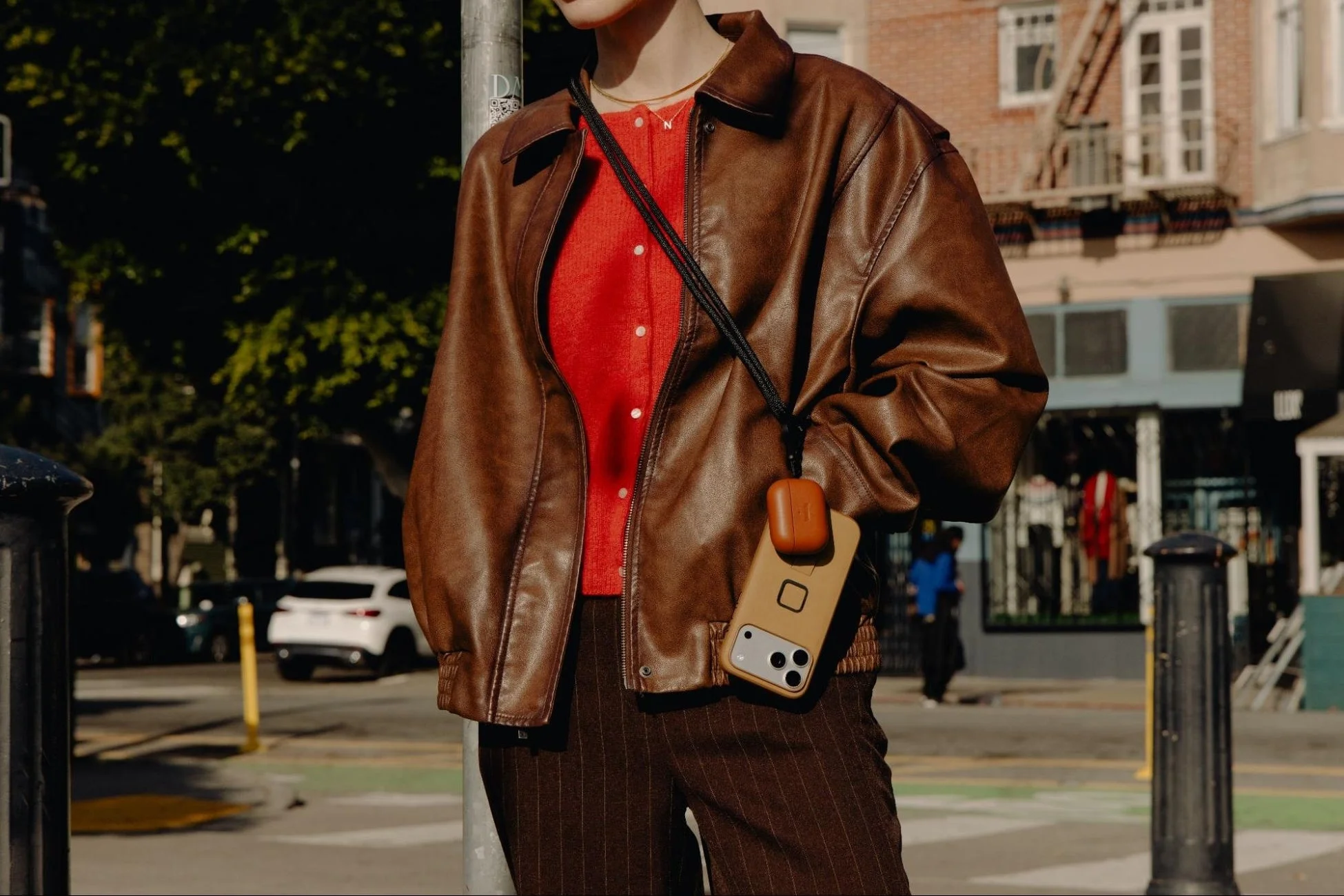 スマホとAirPodsケースをストラップで身につけている