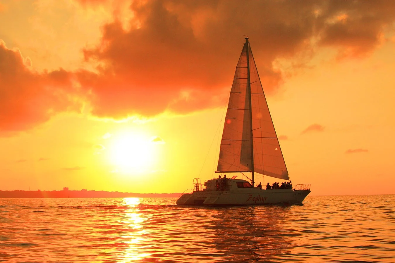 夕焼けに染まる海を航行するカタマランヨット