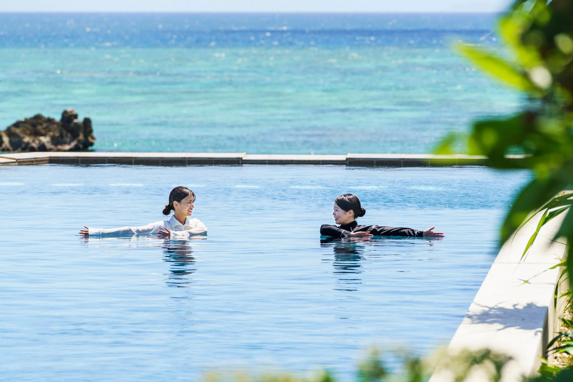 インフィニティプールでリラックスする女性二人