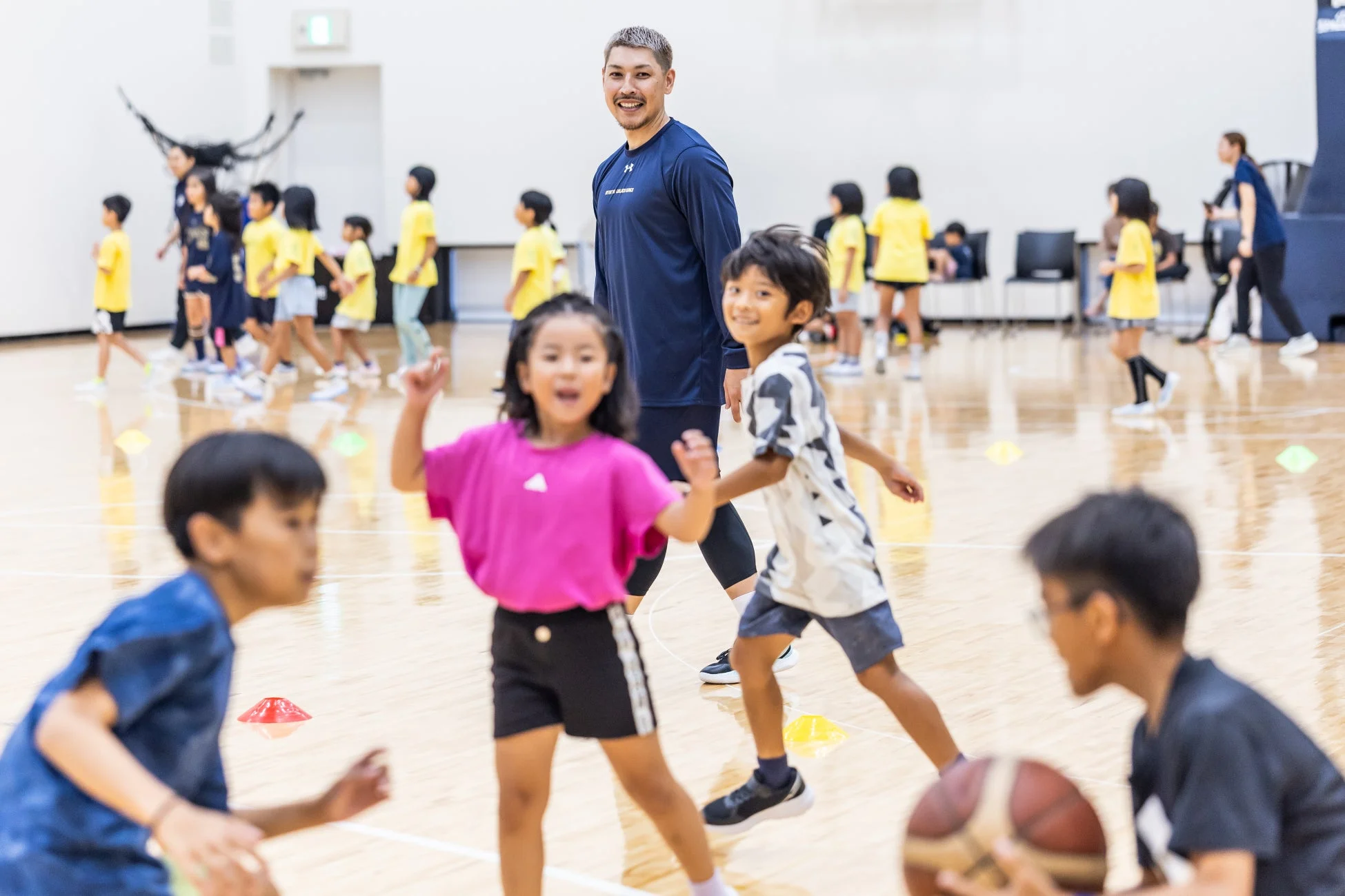 コーチと子どもたちが楽しそうにバスケットボールをする様子