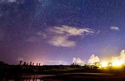 無数の星が輝く夜空と、地平線に広がる光が印象的な夜の風景