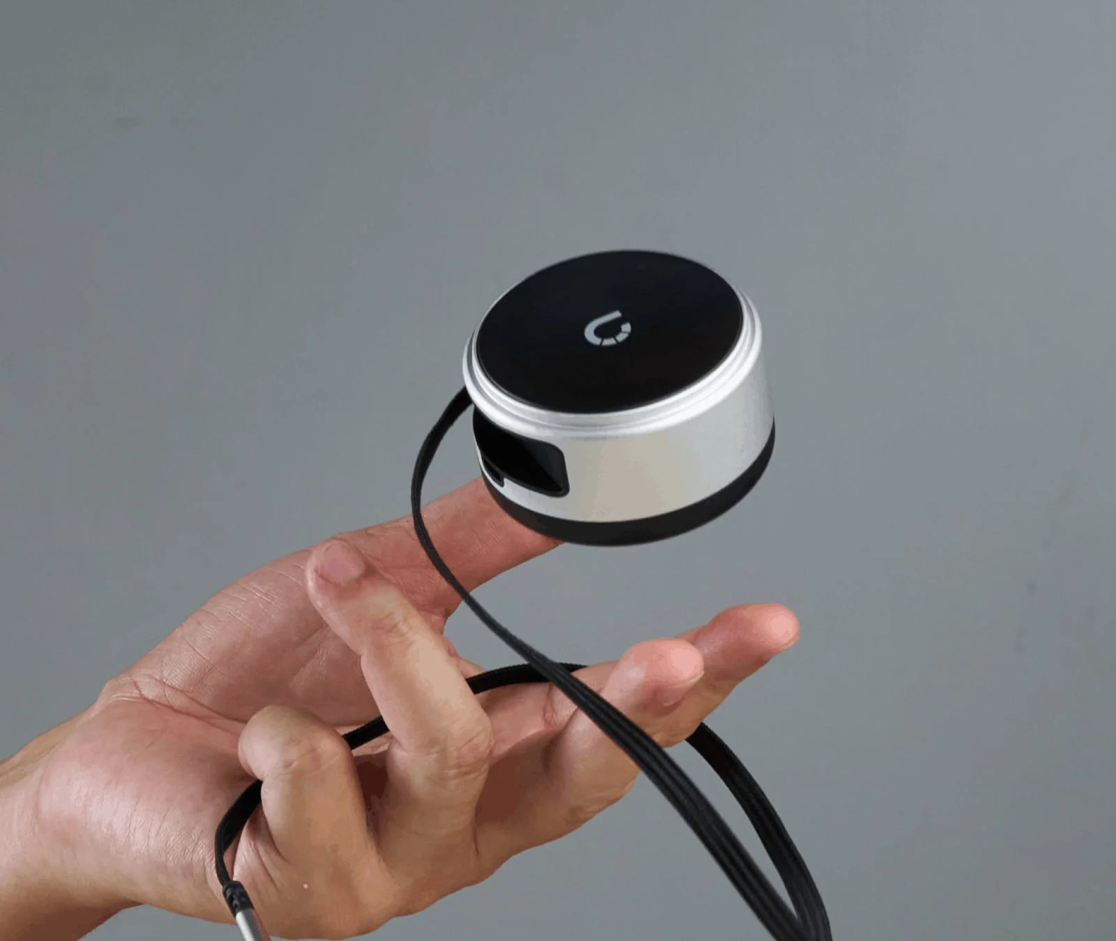 手が小型の円形電子デバイスを指で挟んで持っている