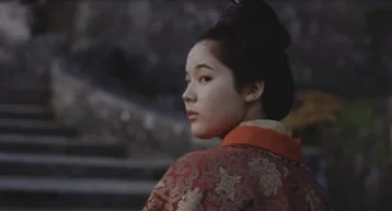 伝統的な着物を身につけた若い女性が、何かを見つめるように後ろを振り返っている横顔のクローズアップ