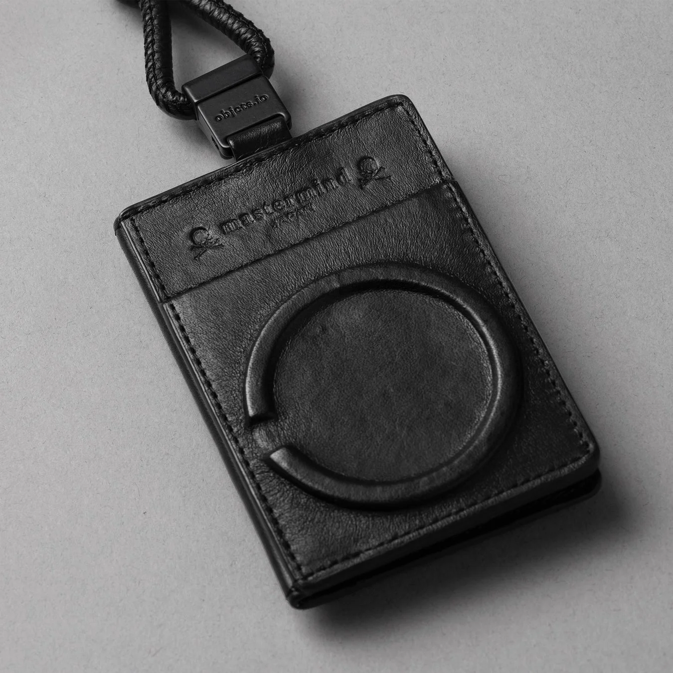 黒い革製のカードケースまたはパスケースで、mastermind JAPANのロゴとobjects.ioの文字が見られます
